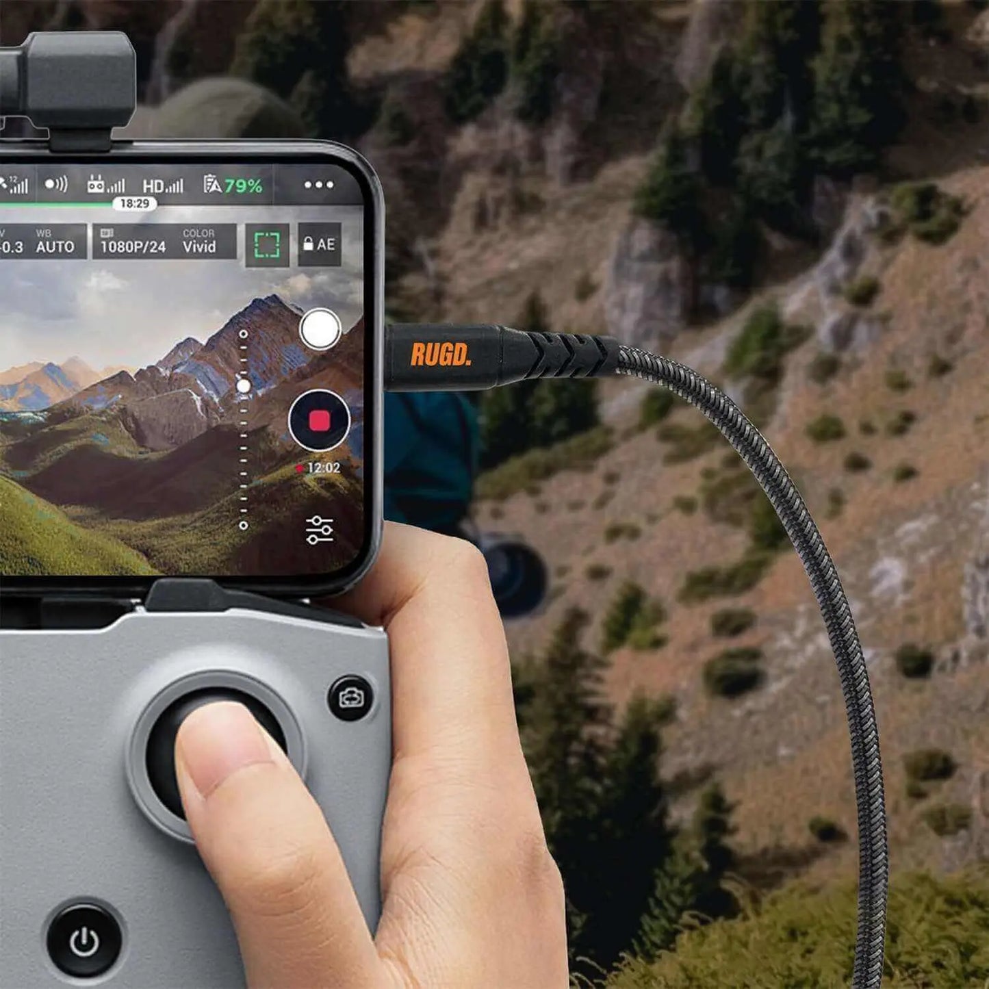 Person using Rhino Power Lightning MFi to USB-C Charging Cable connected to a smartphone and drone controller in a scenic outdoor setting.