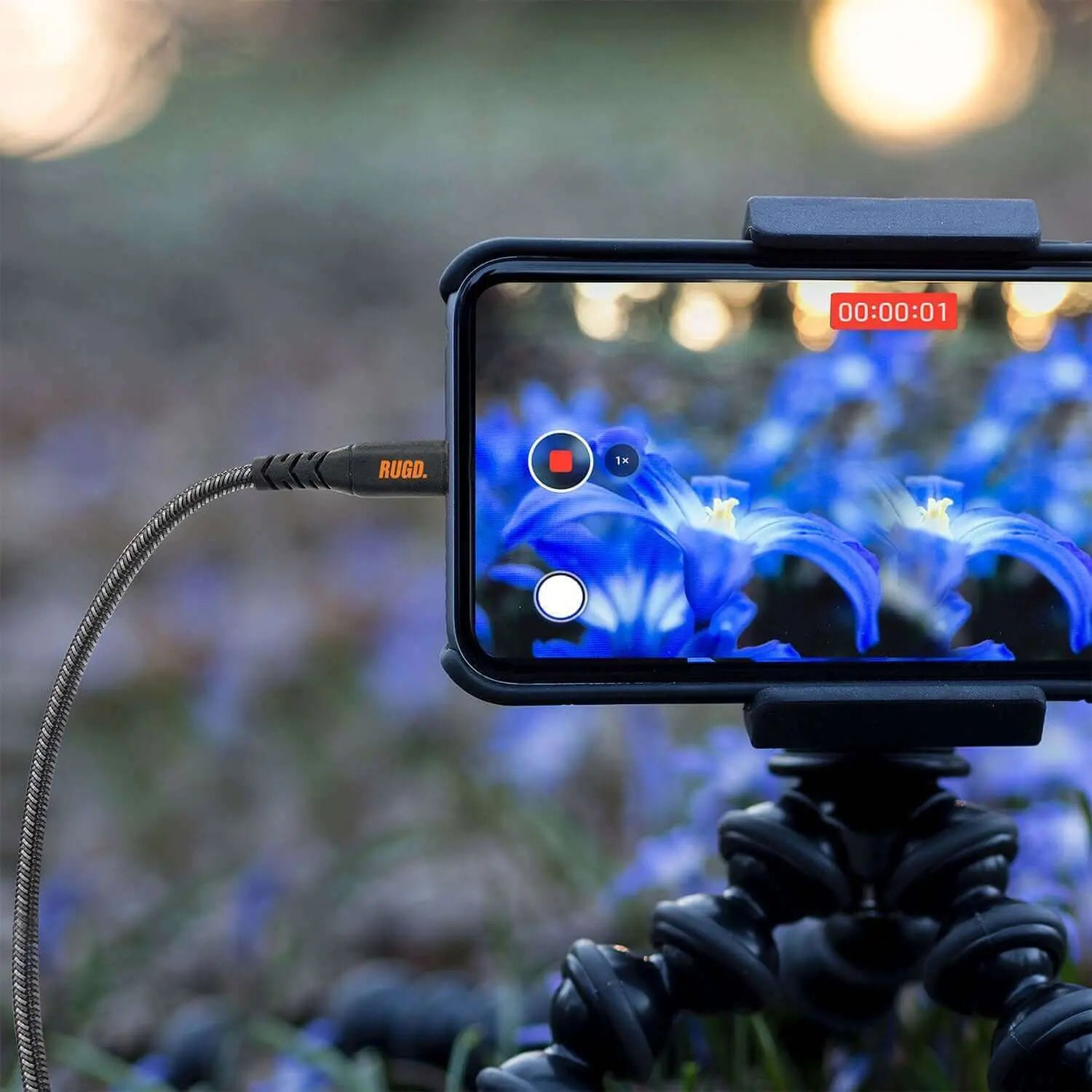 Smartphone with Rhino Power Lightning MFi to USB-C charging cable capturing a video of flowers.