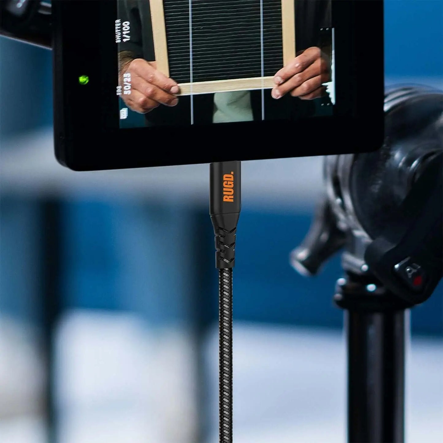 Rugged USB-C charging cable connecting a camera to a monitor