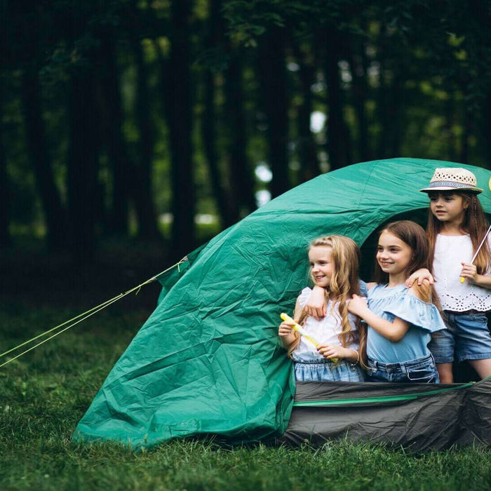 Three kids enjoying a camping trip inside a green tent, showcasing the fun of camping with kids.