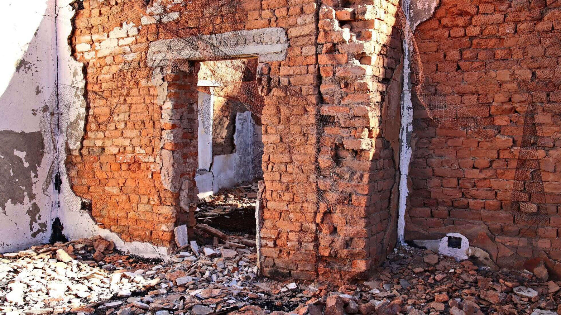 Earthquake damage to a brick building with collapsed walls and debris.