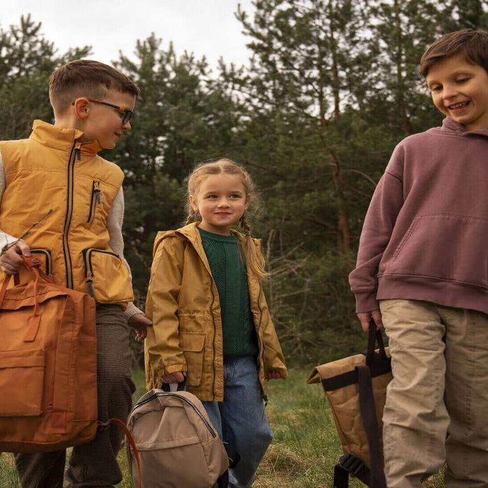 Children happily walking in a forest with camping gear, illustrating a fun and safe family camping trip.