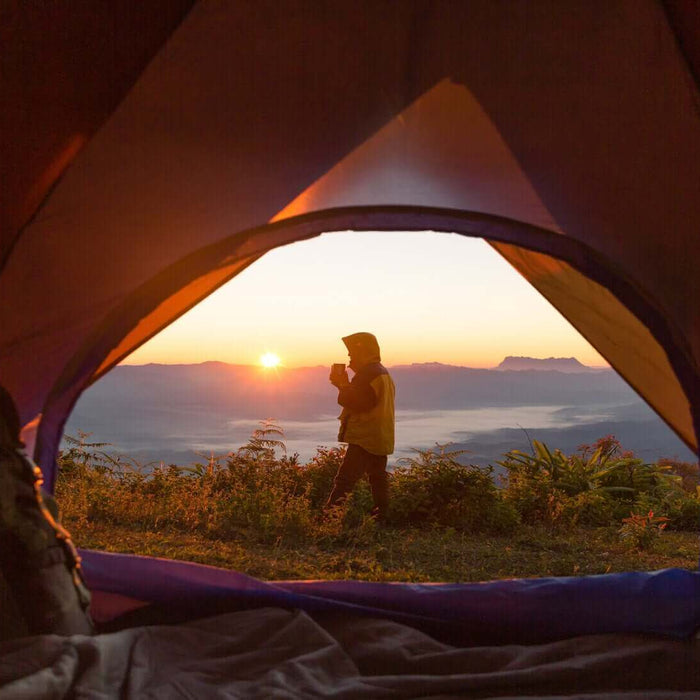 View from inside a tent of a person enjoying a sunrise on an eco camping trip in the UK.