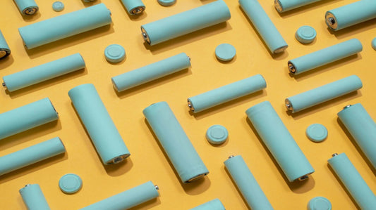 Various sizes of blue cylindrical batteries on a yellow background representing different battery technologies.