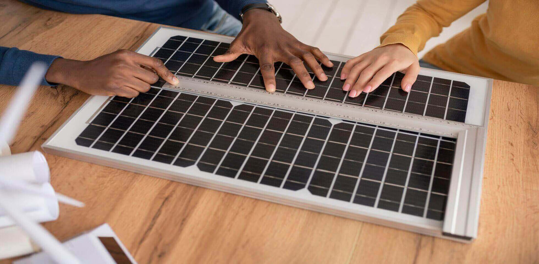 Hands measuring solar panel dimensions on a wooden table