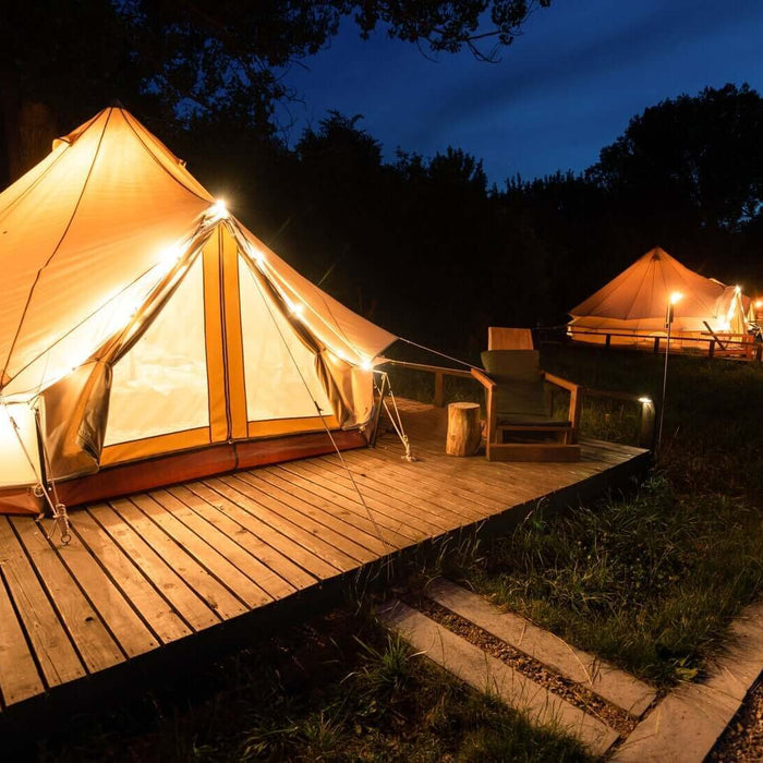 Luxury glamping tents illuminated at night in a scenic UK campsite, offering a blend of comfort and nature