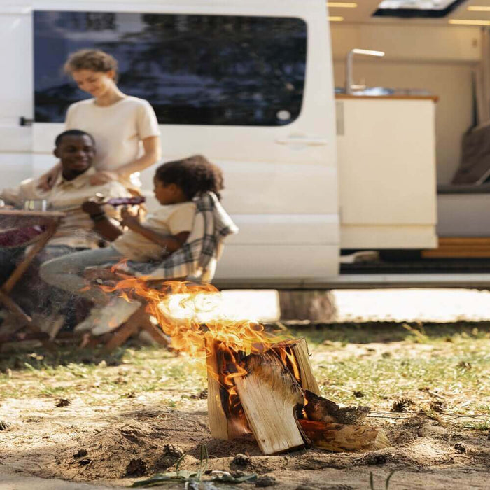 Family enjoying RV camping with a solar-powered generator, sitting by a campfire next to their motorhome in a serene outdoor setting.