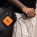 RUGD Power Brick in use, charging a smartphone via USB cables, attached to a black backpack, showcasing outdoor readiness.