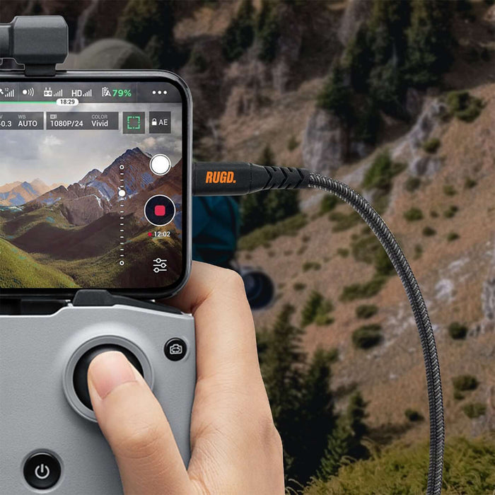 Person using Rhino Power Lightning MFi to USB-C Charging Cable, connected to a device, capturing outdoor nature scenery.